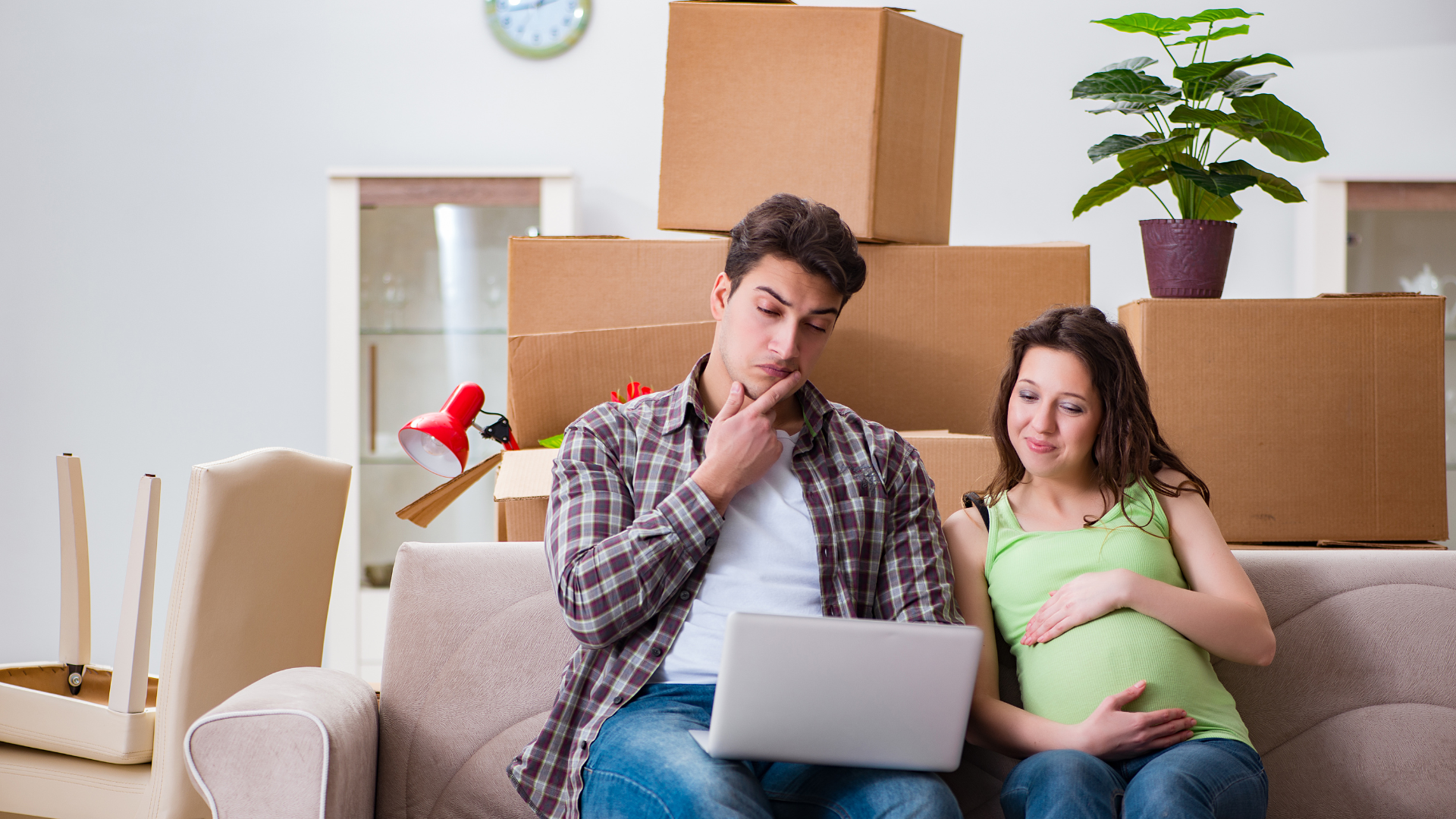 A couple seating on a couch looking and searching for tips and tricks on how to safely move while pregnant