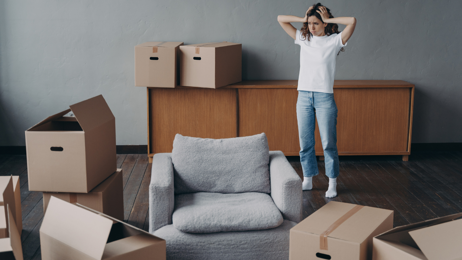 A woman looking at her moving boxes, stressed on her first move.