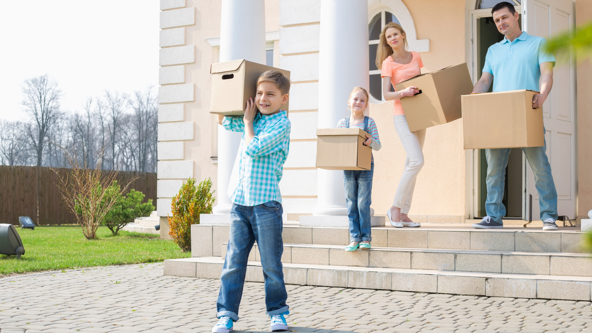 This small family moving out to their house, little boy infront carrying box of stuff followed  by her little sister, Mom and Dad