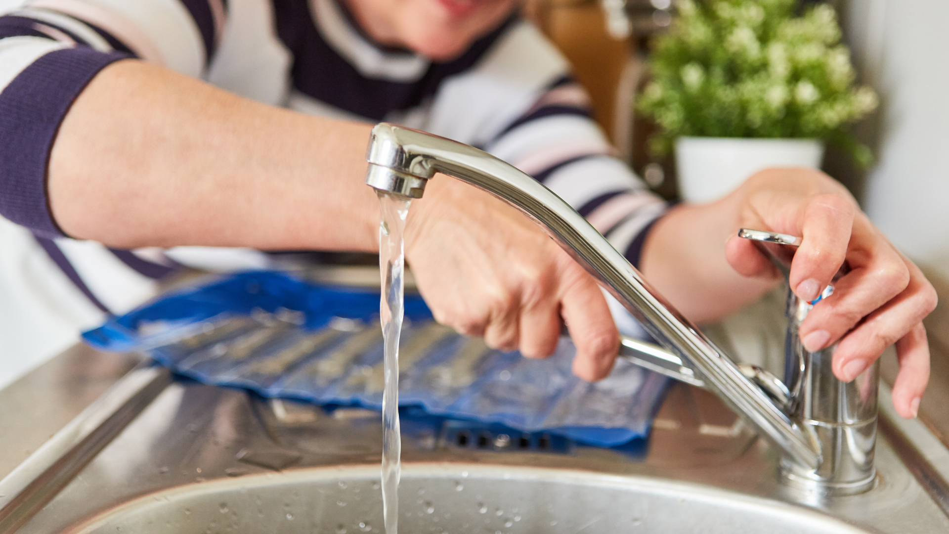 Lady homeowner fixing faucet in her new house. She is using a wrench to carefully fix the leaky faucet.
