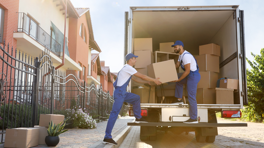 Two movers loading a moving truck outside of an apartment complex