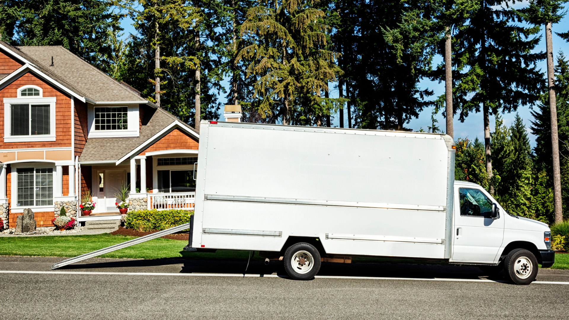<img src=“Moving truck outside home.png” alt=“White rental moving truck outside of a home”>
