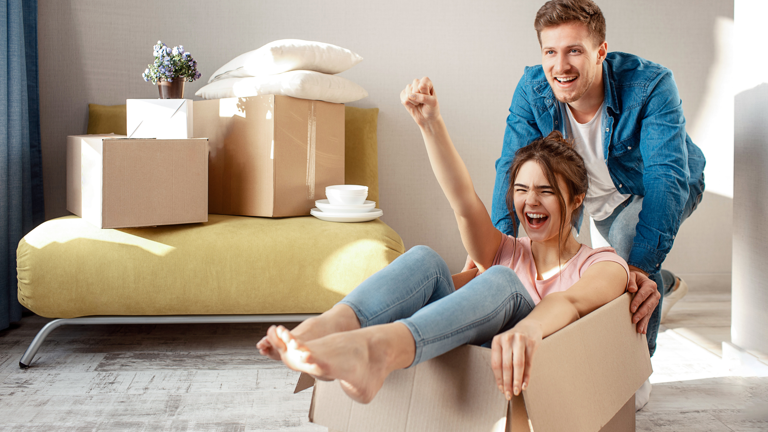 Husband pushing his wife in a cardboard box with excitement