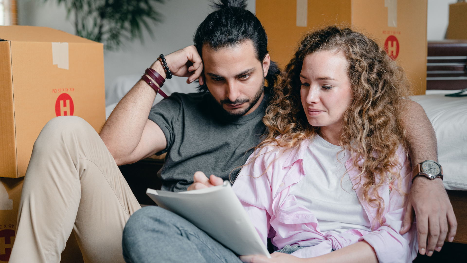 Thoughtful couple writing in notebook while moving house