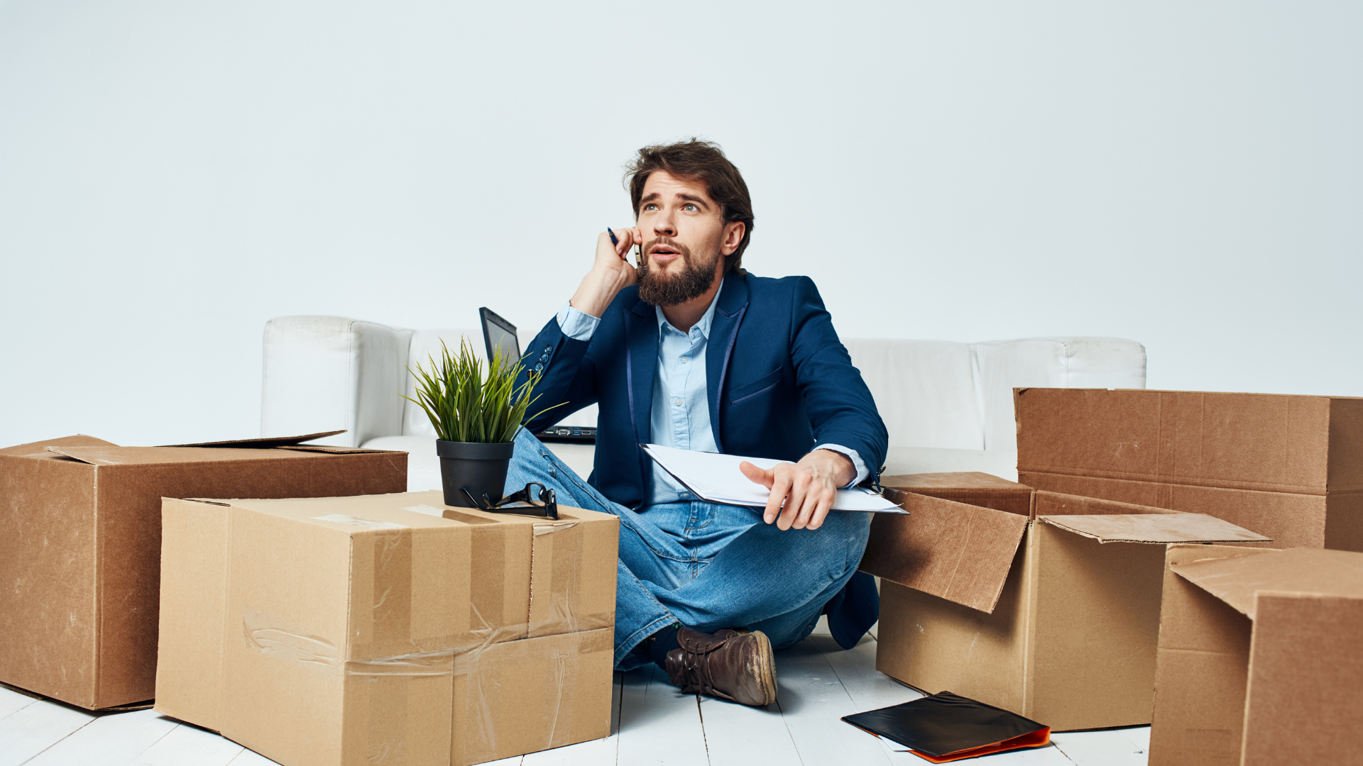 A mover is seating and surrounded with his stuff and planning to move, listing down all the things that needs to know and consider before the moving