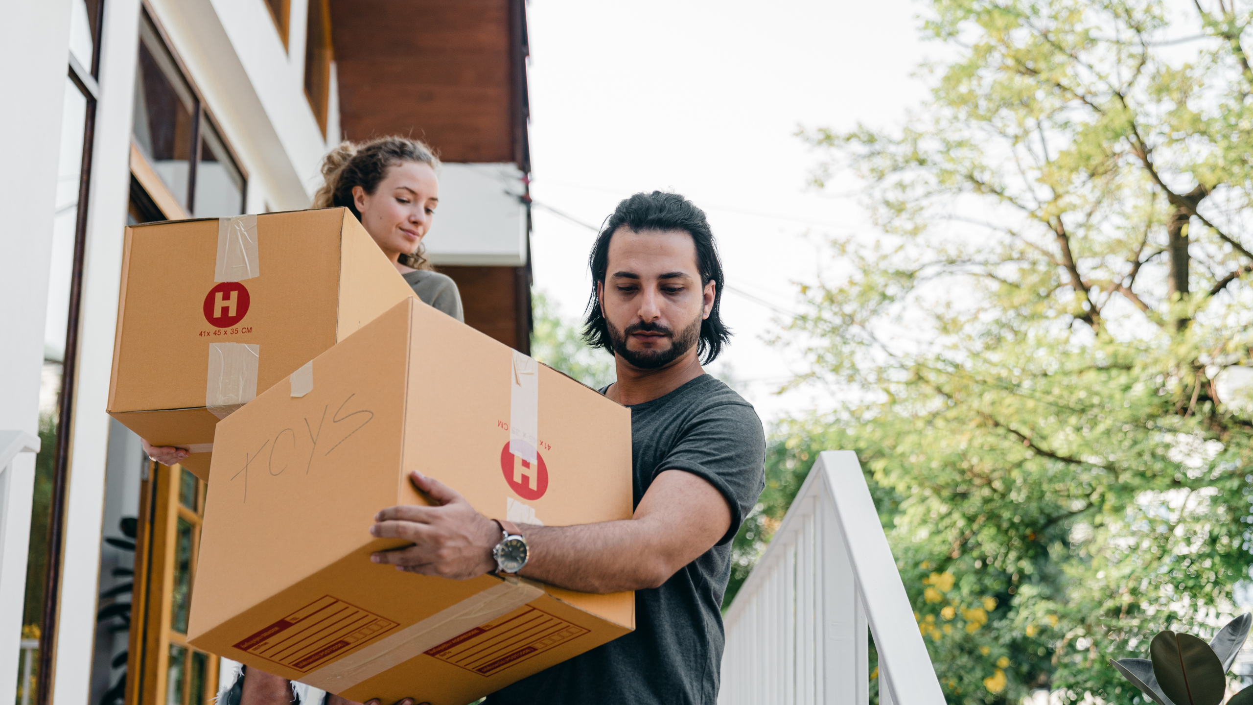 Husband and wife carrying moving boxes down the stairs