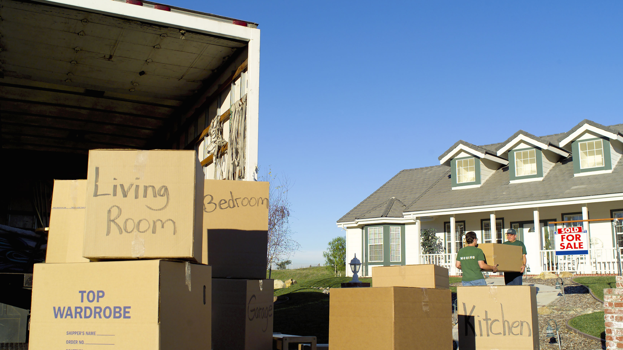 Back of a moving truck outside of a home with lots of boxes