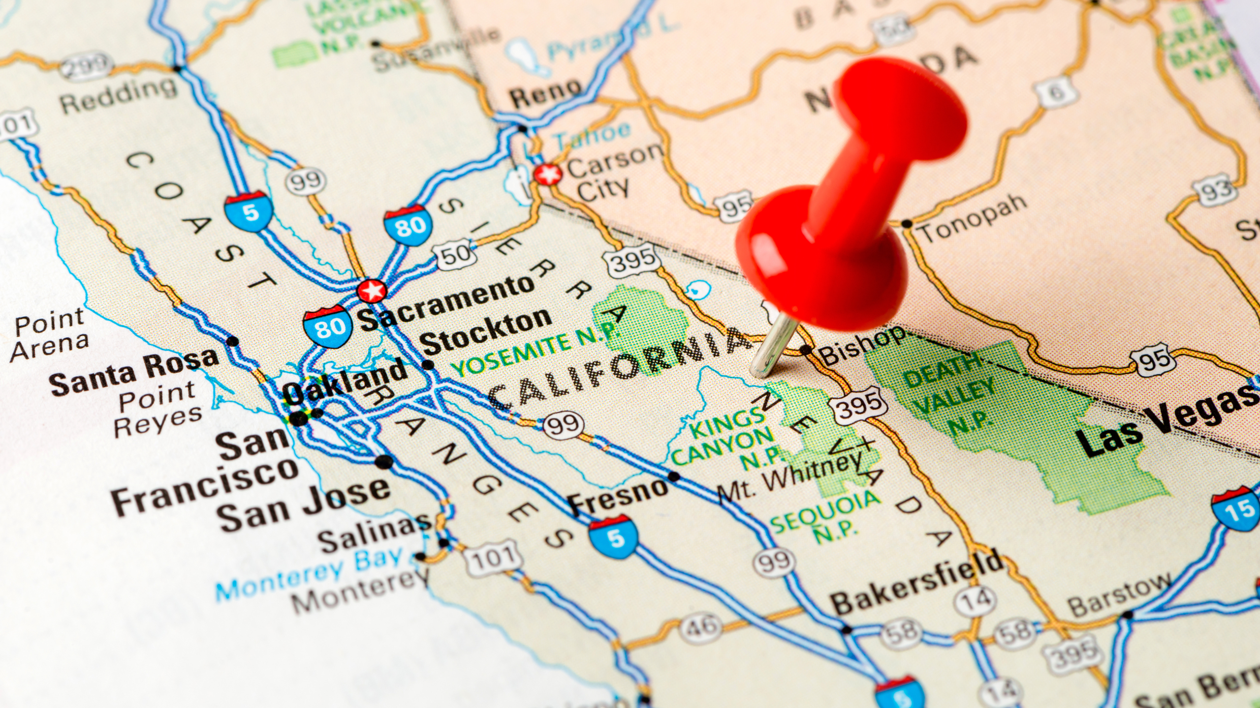 Close up picture of a map with a pin in California 
