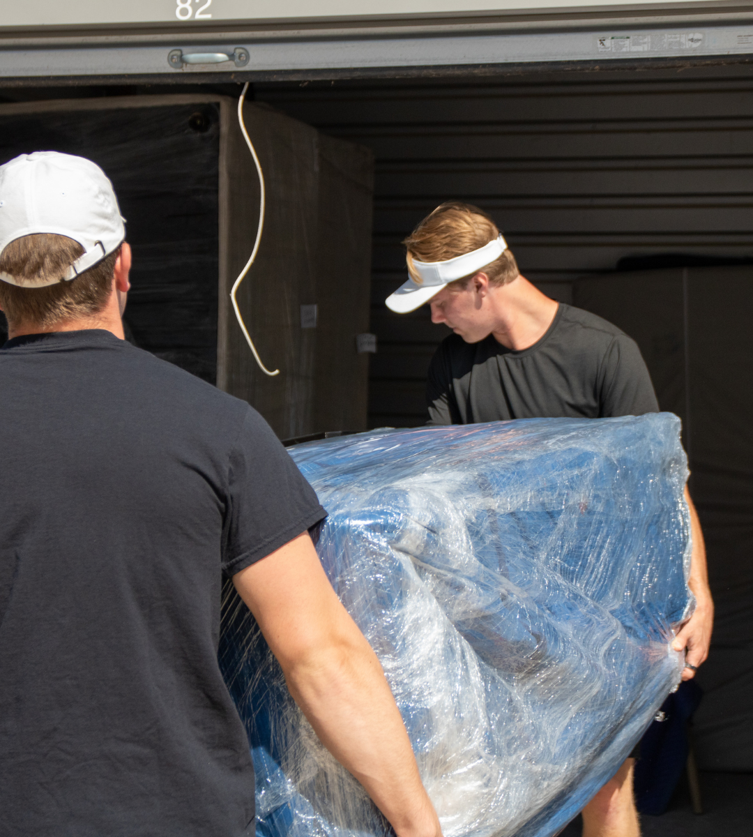 alt="two man carrying a sofa"