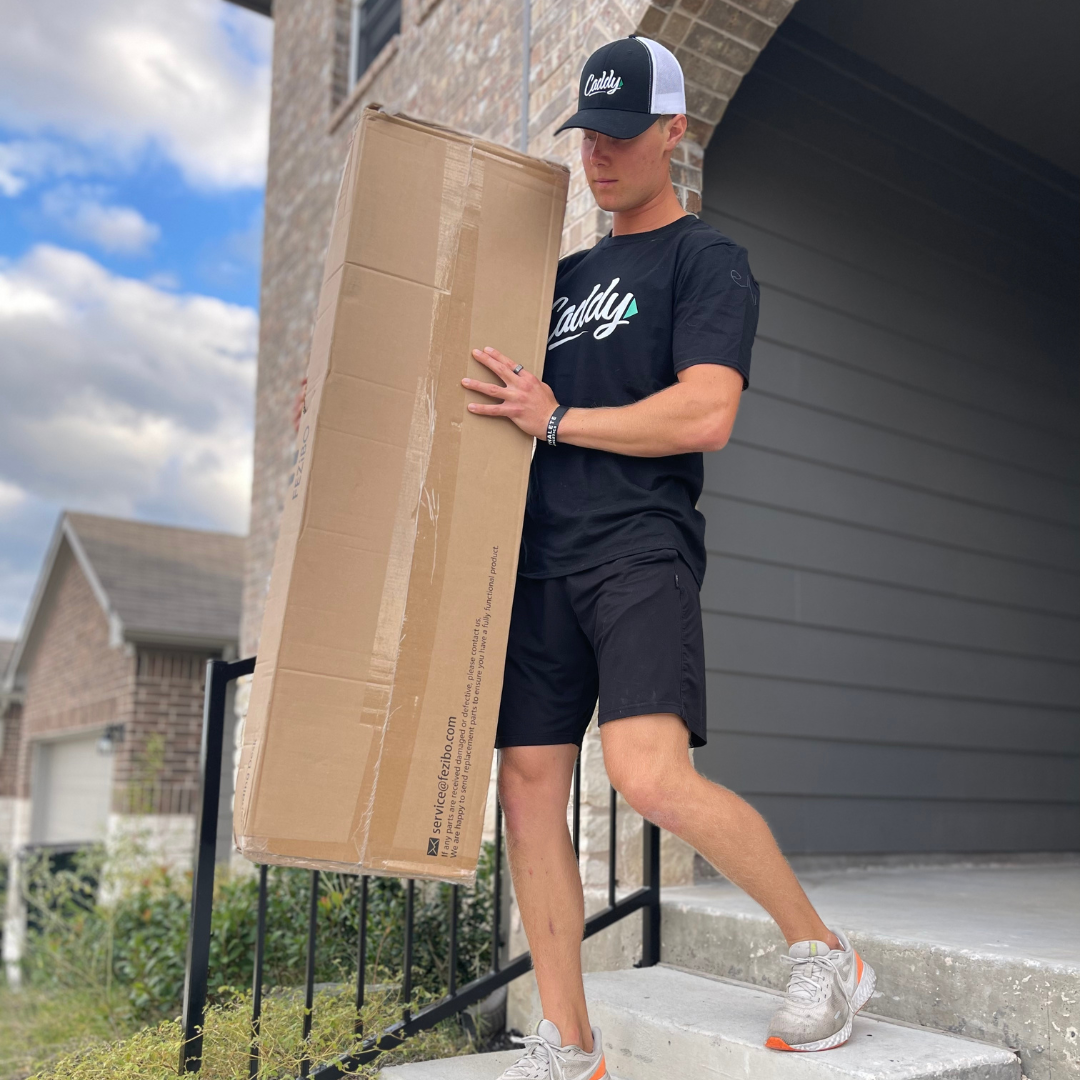 alt="Caddy mover carrying a vertical moving box down a flight of stairs outside a house"